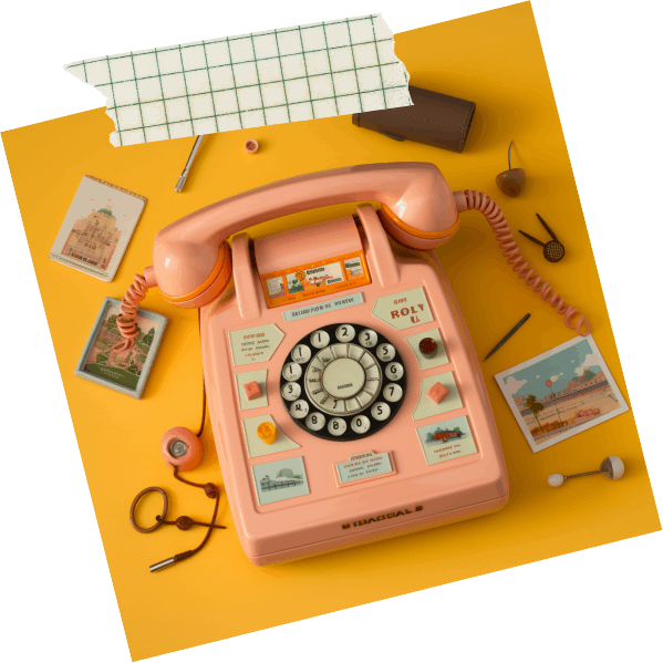 a vintage pink telephone surrounded by vintage stationery on a yellow desk