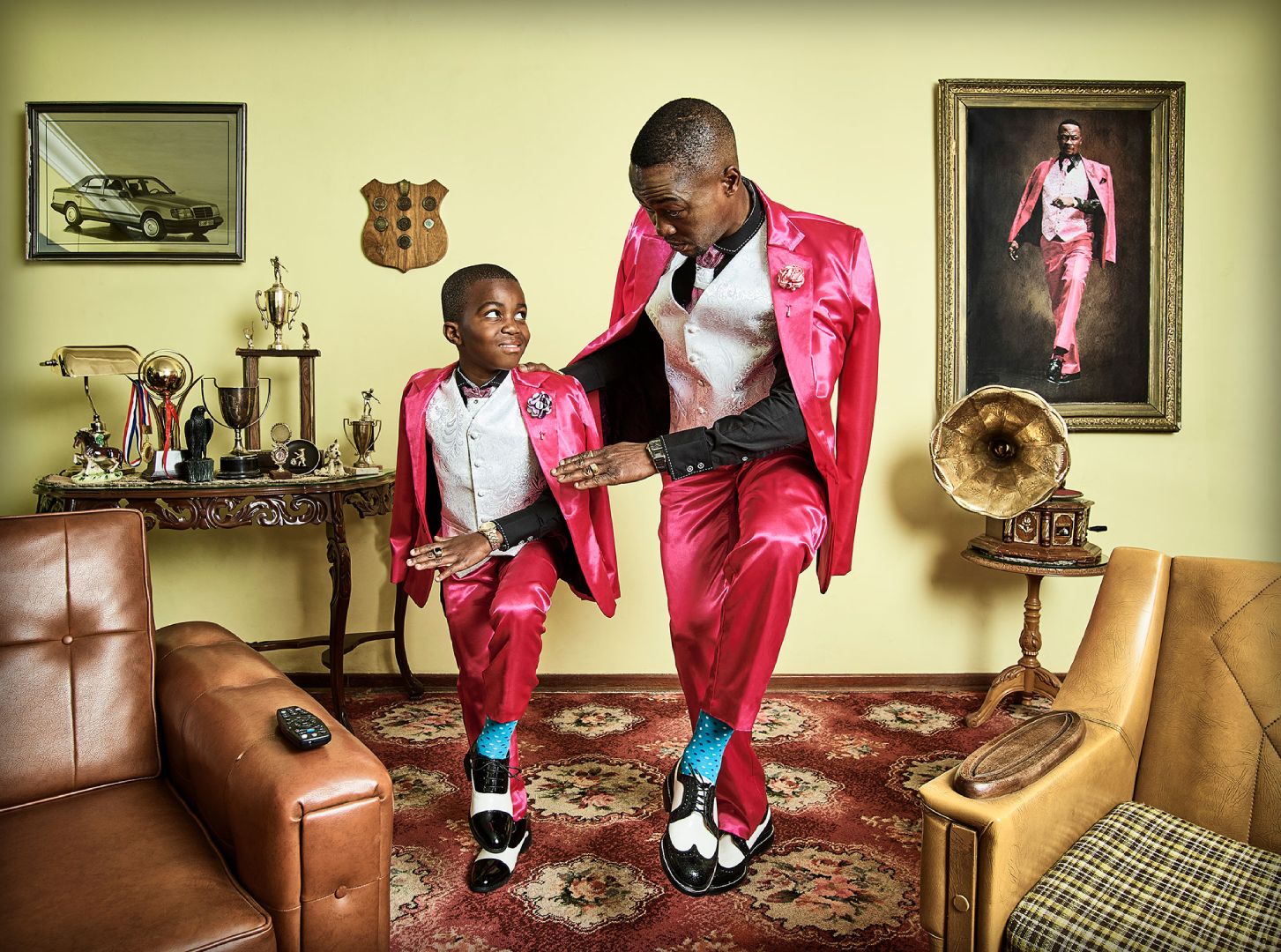 A father and sone dressed in bright pink silk suits with father teaching his son the traditions of swanko dance routine